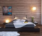 Black platform bed with a modern wood clad bedroom wall