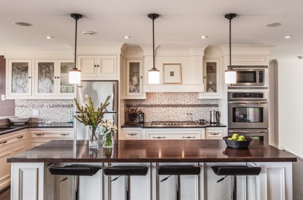 Dazzling pendant lights above a white kitchen island with dark granite