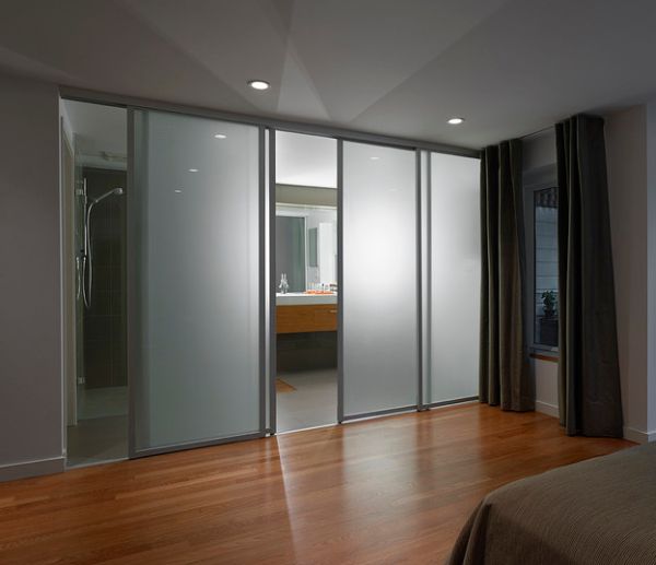 Frosted glass sliding doors separate the contemporary bedroom from the sleek bathroom