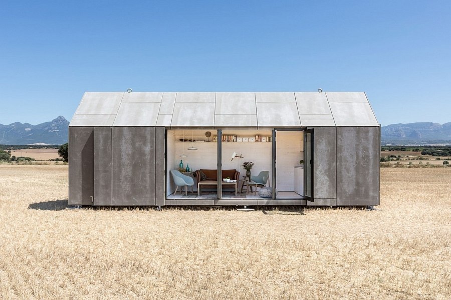 Sliding cement panels and glass doors connect the small portable house with outdoors