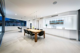 Dark chairs and a wooden dining table bring contrast to the minimalist setting
