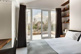 Plush bedroom with private balcony and view of the rear garden