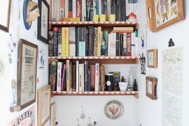 Shelves of the eclectic powder room are decked out with books