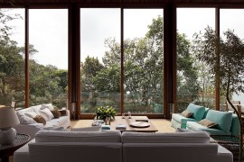 Outdoor sitting area in a glass enclosure with a view of the forest and the ocean