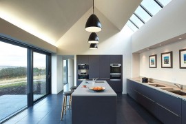 Contemporary kitchen design with large windows, skylights and black pendant lights