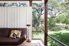 Large glass windows open up the sitting area to the lush green landscape outside