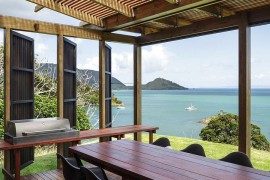Outdoor dining space under pergola with stunning sea views in New Zealand