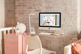 Small corner workspace with transparent desk and a pastel pink cabinet