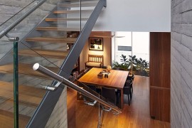 Staircase with wooden steps and glass railing inside the contemporary home
