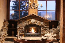 Fabulous cabin-style bathroom with copper bathtub, fireplace and large windows