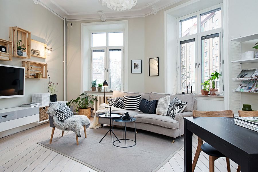 This Scandinavian living room features a light and airy feel with a plush couch, coffee table, and area rug in neutral tones. A black accent chair adds a touch of contrast.