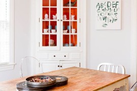 Pops or orange inside the corner cabinet add a touch of playfulness to the dining room