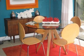 Rug and wall art bring orange into this midcentury dining room