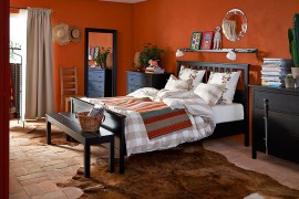 Dark chest of drawers ground the vivacious bedroom in bold orange