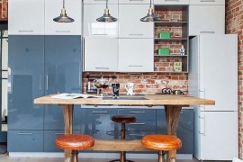 Glossy modern kitchen cabinets stands in contrast to the brick wall backdrop