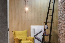 Lovely reading nook with brick wall, bright yellow chair and a stylish ladder used as book rack