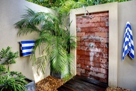 Outdoor shower with palm fronds and striped towels