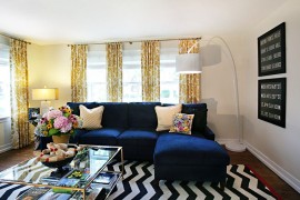 Plush couch in navy blue and coffee table in glass and gold for the trendy living room [Design: Debbie Basnett, Vintage Scout Interiors]