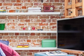 Sleek floating shelves and TV stand for the tiny living room with brick walls