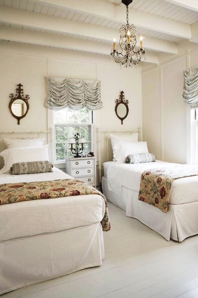 Clean and elegant twin beds paired with chandelier and mirrors