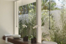 Earthy modern bathroom overlooking tropical plants