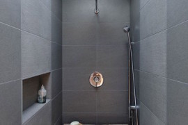 Rustic wood bench in a modern dark tiled bathroom