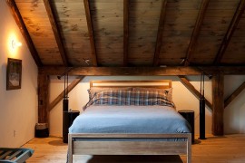 Stained wooden slanted ceiling adds to the rustic charm of the cozy bedroom