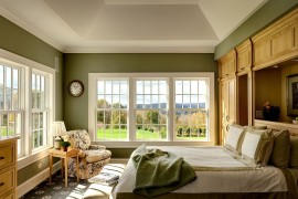 Traditional bedroom in green and white with large windows