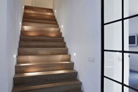 Very small light fixtures on each wall along a wood staircase