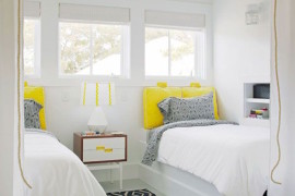 Very white guest room with bright yellow twin bed pillows