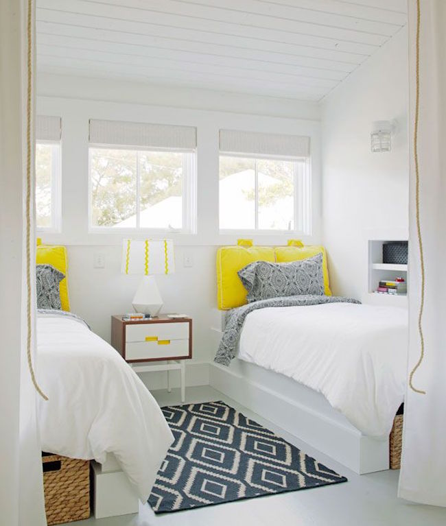 Very white guest room with bright yellow twin bed pillows