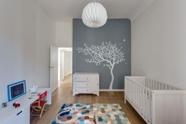 Wall mural blends into color scheme of the nursery while rug brings geometric class