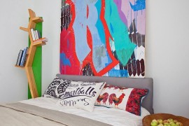 Bookcase, pillows and wall art add color to the white bedroom