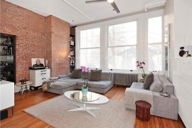 Exposed brick wall with blackened steel book shelves in the modern family room [Design: kimberly peck architect]