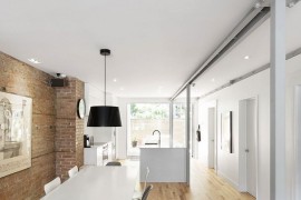 Natural birch flooring and exposed brick wall give the interior a cozy vibe