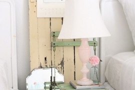 Old chair, vintage door and lovely lamp make the bedside area a shabby chic delight