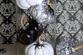 Pumpkins painted black and white in glass cylinder