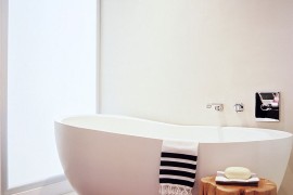 Tree stump stool used as side table next to the bathtub