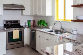 WIndow frame adds a bright spark of yellow to the white kitchen with stone countertops