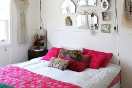 Wire pendant lights, bright accent pillows and colourful bedding shape the shabby chic bedroom