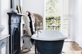 A fireplace and matching clawfoot tub in a bathroom with a balcony
