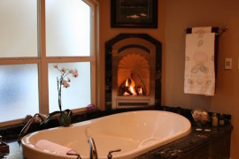 A luxurious tub with a small nearby fireplace