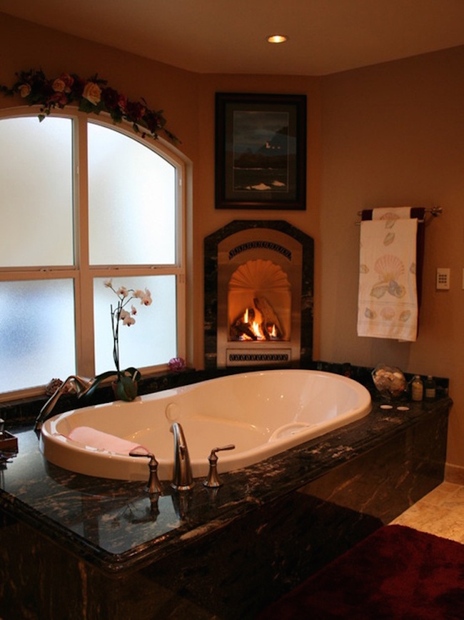 A luxurious tub with a small nearby fireplace