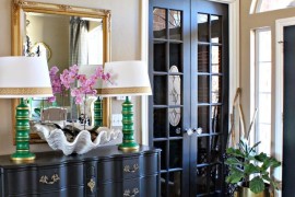 Bold and eclectic entryway with a gold framed mirror and antler decor above it