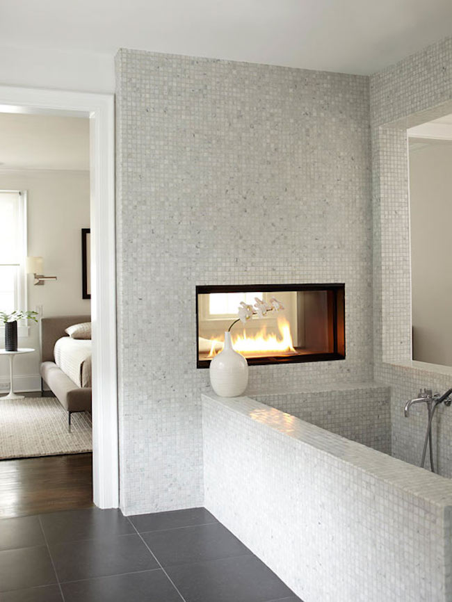 Dual fireplace in a marble tiled bathroom