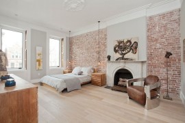 Exposed brick walls and classic fireplace inside the Scandinavian bedroom [Design: Jensen C. Vasil Architect]