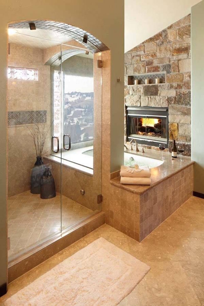 Fireplace built into stone wall in front of alcove tub