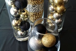 Gold, black, and silver Christmas ornaments in glass cylinders