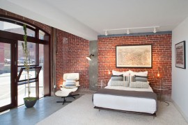 Gorgeous bedroom with brick wall, concrete flooring and midcentury décor [Design: Rockefeller Partners Architects / Tara Wujcik Photography]