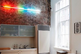 Interesting use of lighting highlights the exposed brick wall in the double height kitchen